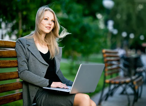 Mujer de negocios sentada en el banco en el parque con cuaderno Imagen De Stock