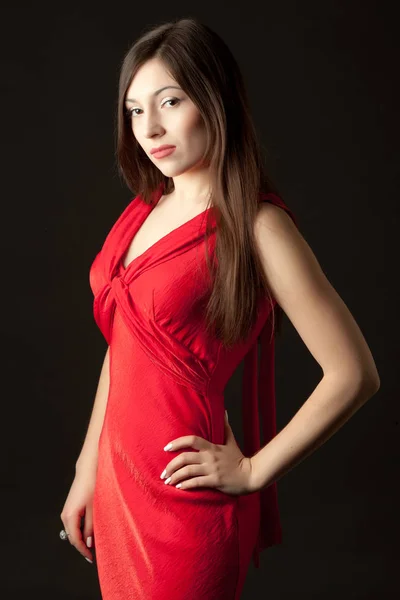 Young woman in red cocktail dress standing over dark background — Stock Photo, Image