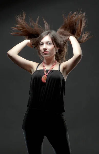 Young brunette woman in black casual clothing turning head with windy hair — Stock Photo, Image