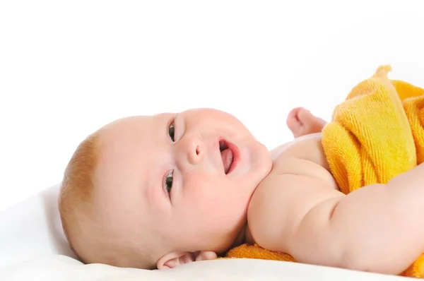 Leuke baby ligt onder gele deken — Stockfoto