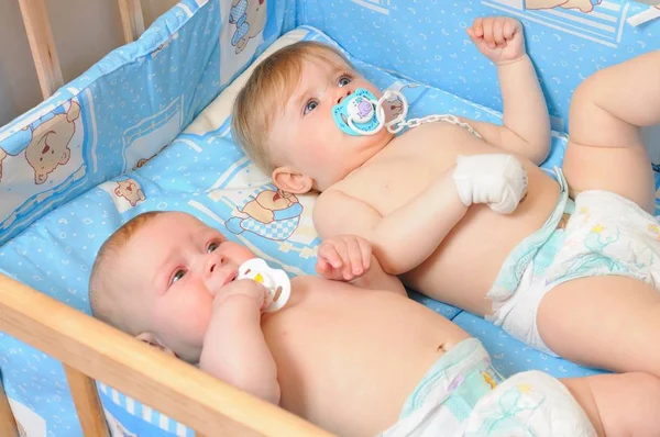 Two babies lying in wooden crib — Stock Photo, Image