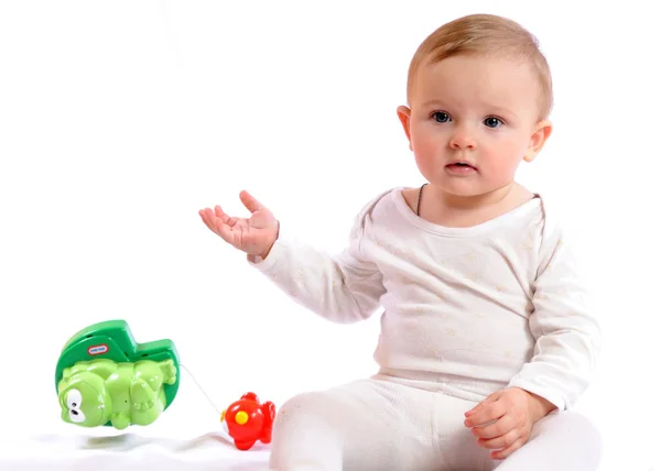 Ребенок сидит рядом с детскими игрушками — стоковое фото