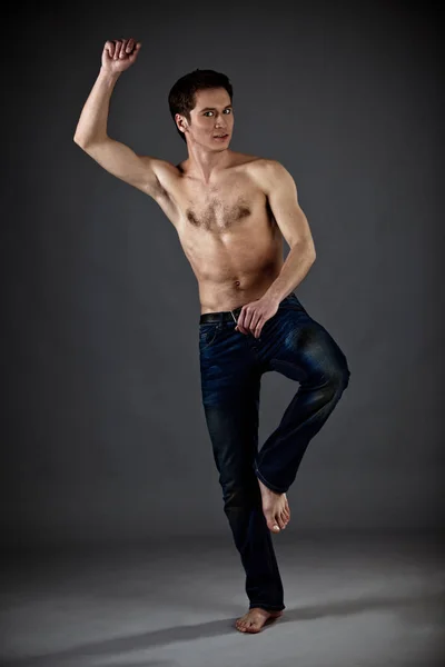 Joven atlético con torso desnudo en jeans de pie sobre fondo negro — Foto de Stock