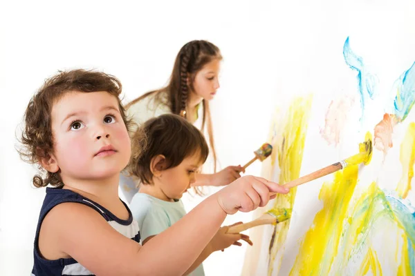 Tre barn målar med penslar och färger — Stockfoto