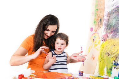 Kadın ve bebekler masada otururken resim çiziyorlar.