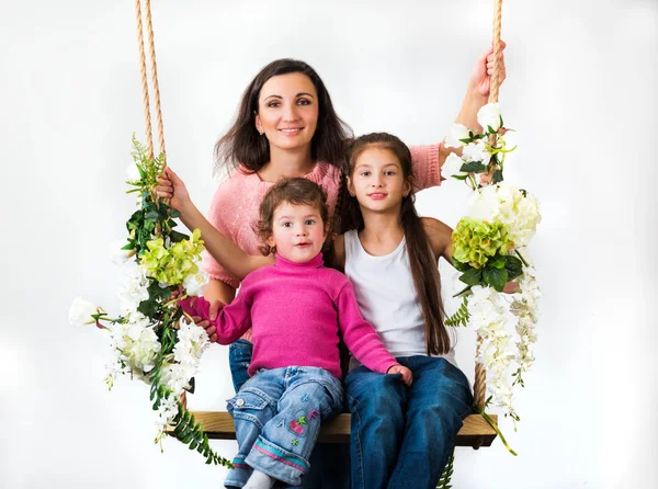 Família sentada em um balanço de flores — Fotografia de Stock