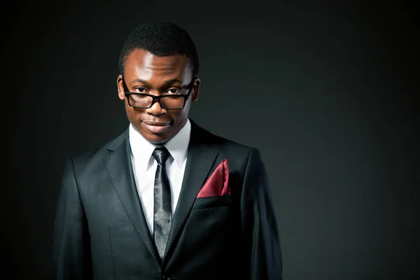 Joven hombre de negocios africano guapo en traje gris, camisa blanca, corbata y gafas de pie y sonriente —  Fotos de Stock