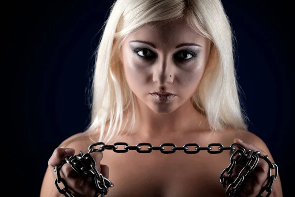 Young beautiful blond woman standing and holding massive chains in hands over black background — Stock Photo, Image