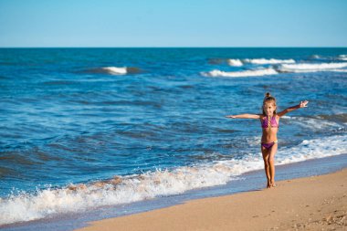 Mutlu küçük kız kumlu sahilde koşuyor
