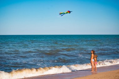 İki neşeli kız kardeş uçurtmayla oynuyorlar.