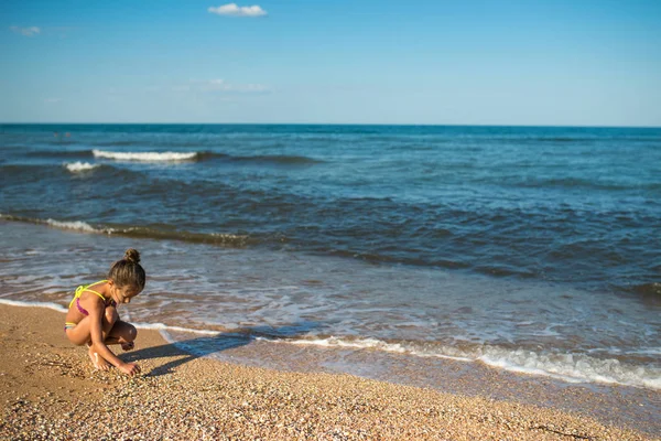 Petite fille solitaire écrit quelque chose sur le sable — Photo