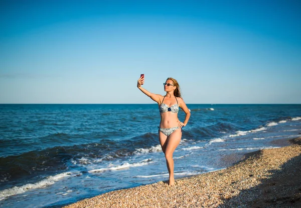 Beautiful young woman in a swimsuit makes selfie — 스톡 사진