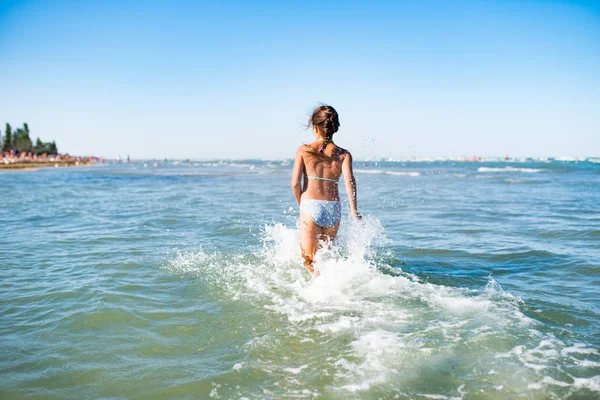 Rear view of positive little girl running on water — 스톡 사진