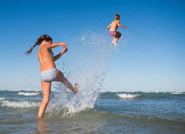 Niña lanza a su hermana saltando en olas — Foto de Stock