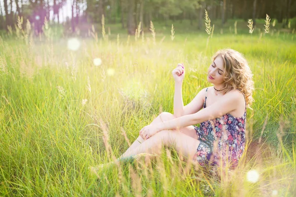 Güzel, dişi, genç bir kız çimlerin üzerinde oturuyor. — Stok fotoğraf