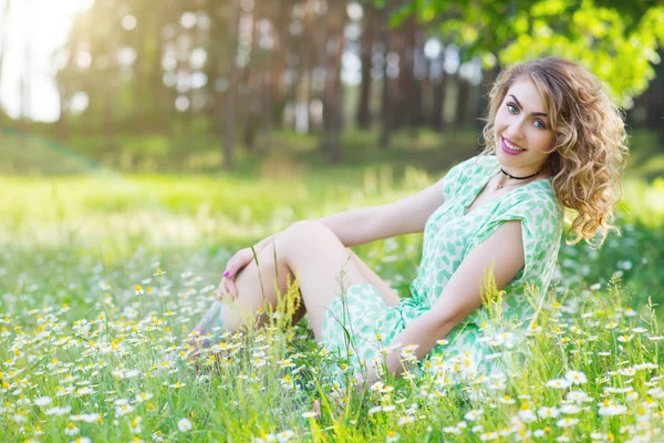 Gyönyörű, nőies fiatal lány ül a fűben. — Stock Fotó