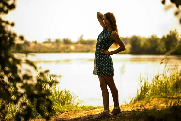 Young woman standing and enjoying summer day with lake at background — 스톡 사진