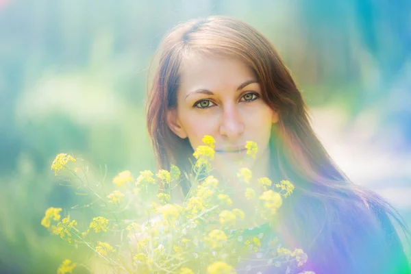 Sarı çiçekleri tutan yeşil gözlü güzel bir kadın. — Stok fotoğraf