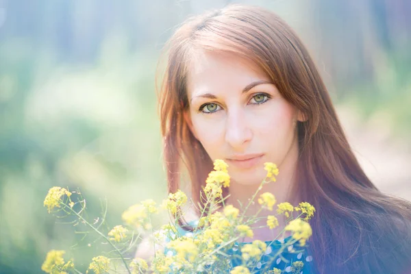 Mujer hermosa joven con ojos verdes sosteniendo flores amarillas — Foto de Stock