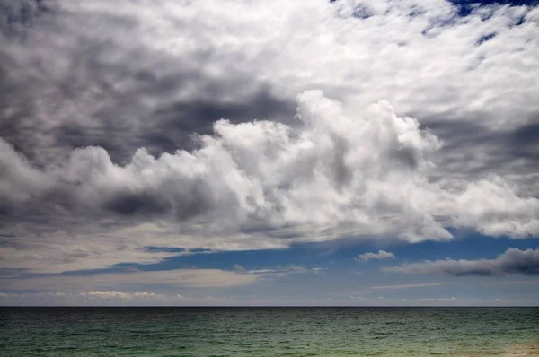 Wybrzeże morskie i skalista plaża, błękitne zachmurzone niebo — Zdjęcie stockowe