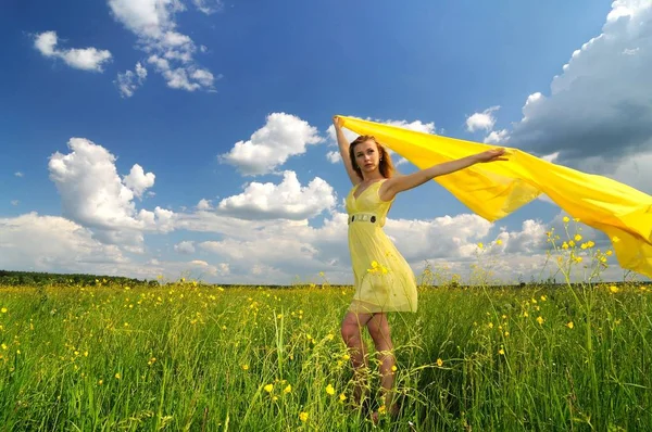 Девушка позирует в поле с шелковой тканью в руках — стоковое фото