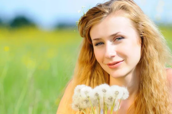 Portrait of a young girl with dandelions in her hands — Stock Photo, Image
