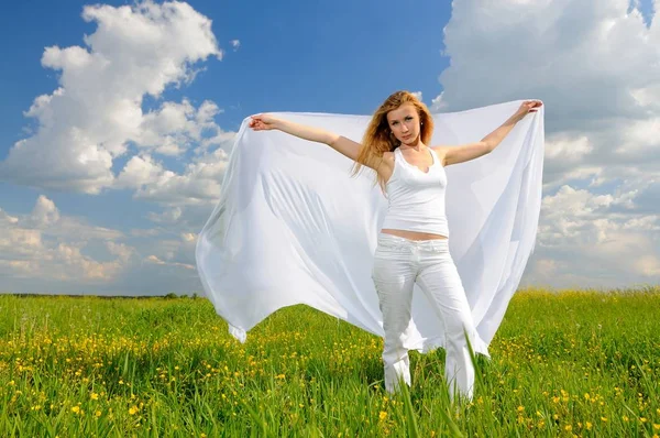 Vrouw in bloemenveld met zijden doek in haar handen — Stockfoto