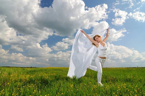 Женщина в цветочном поле с шелковой тканью в руках — стоковое фото