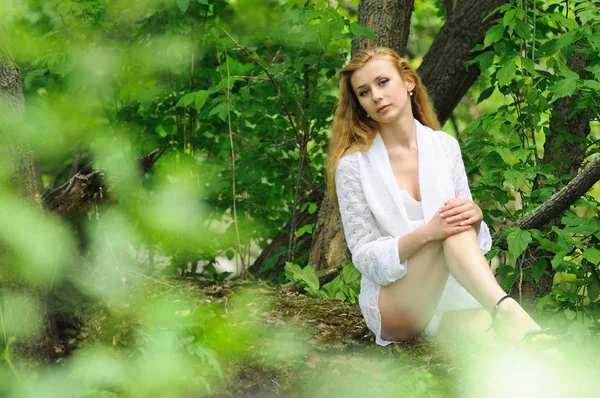 Beautiful girl posing sitting on a log — 스톡 사진