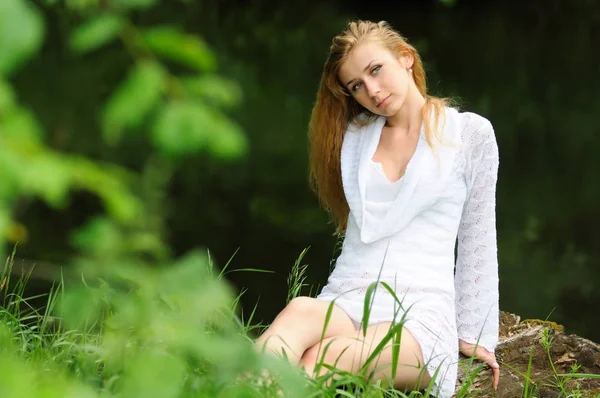 Beautiful girl posing sitting on a log — 스톡 사진