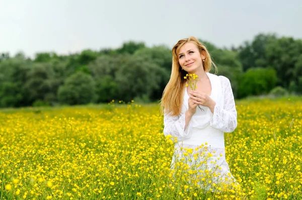 Junge Frau posiert in einem Blumenfeld — Stockfoto