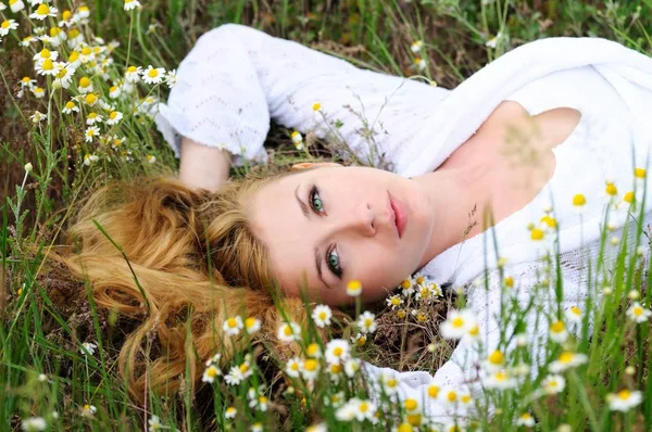 Schattig meisje ligt op het gras en bloemen — Stockfoto