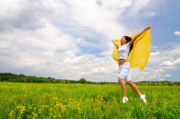 Young smiling woman standing with silk shawl in meadow — ストック写真