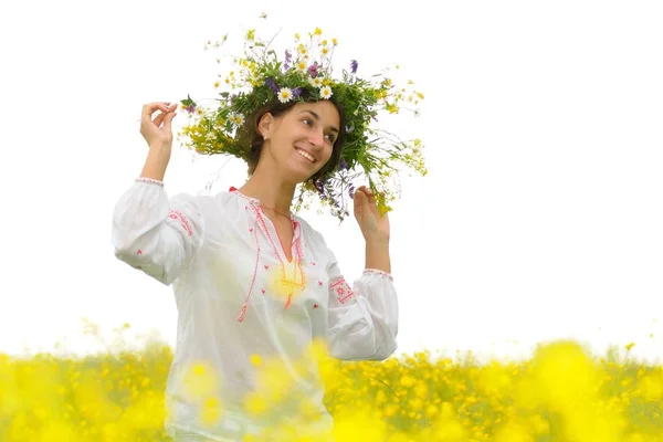Mujer sonriente en ropa nacional y corona de flores de pie en el prado — Foto de Stock