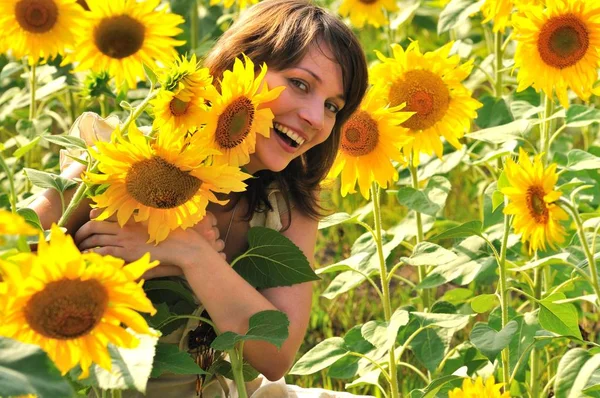 Meisje in bloemenveld met zonnebloem in handen — Stockfoto