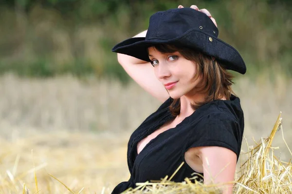 Dívka v kovbojském klobouku sedí na kupce sena — Stock fotografie
