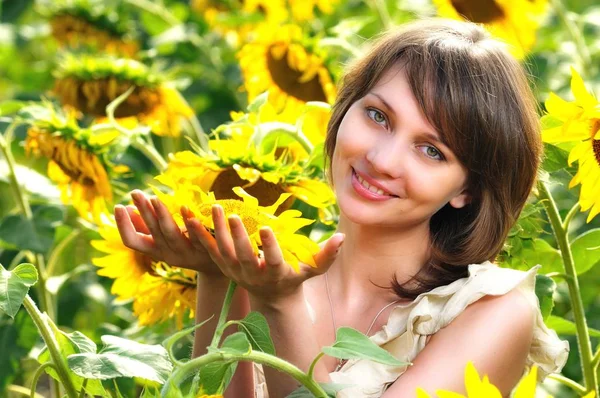 Meisje in bloemenveld met zonnebloem in handen — Stockfoto