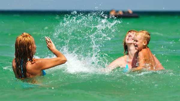 Duas mulheres jovens e menino pequeno de pé e gostando de estar na água — Fotografia de Stock