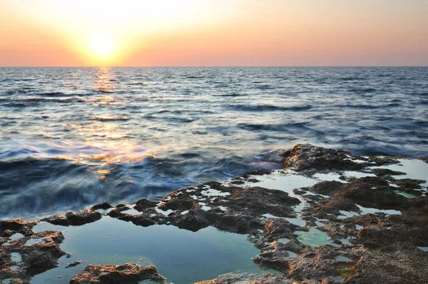 Beautiful pink sunset and water stones over Black sea rocky coastline in Crimea