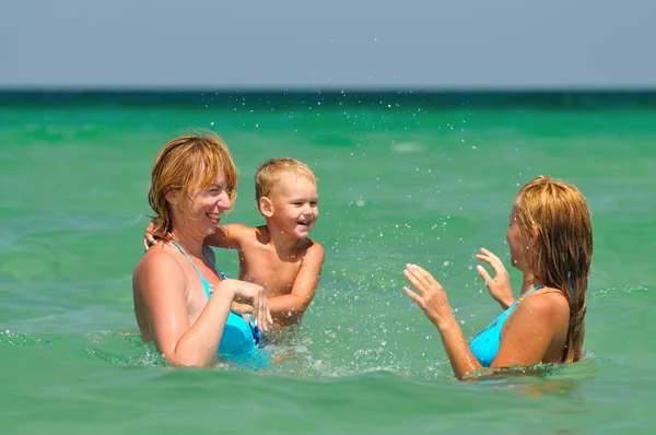 Dos mujeres jóvenes y un niño pequeño de pie y disfrutando de estar en el agua —  Fotos de Stock
