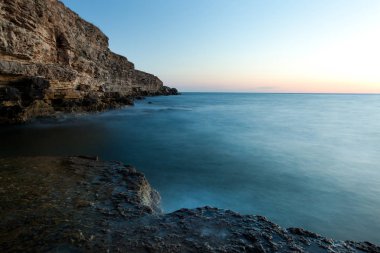 Yazın Kırım 'da dalgalı fırtınalı Karadeniz kıyısında güzel bir gün batımı.
