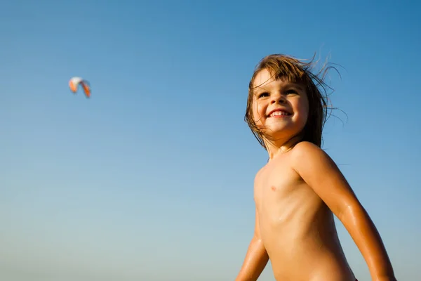 Niña feliz corriendo en el borde del agua de mar bajo el sol y sonriendo — Foto de Stock