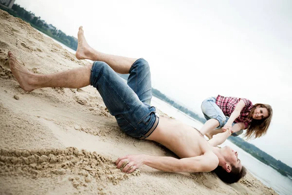 Ung kvinna släpar sin pojkvän på sandig mark på sommaren dag med grön natur i bakgrunden — Stockfoto