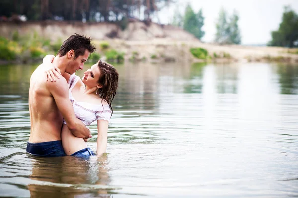 Jovem lindo casal amoroso em pé na água parada e olhando um para o outro no dia de verão — Fotografia de Stock