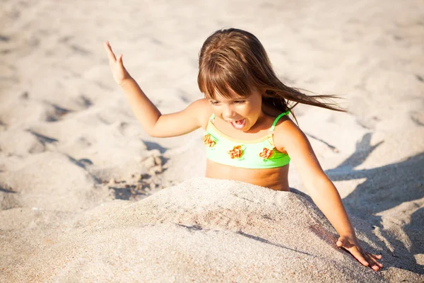 Niña sentada y jugando con arena en la playa —  Fotos de Stock