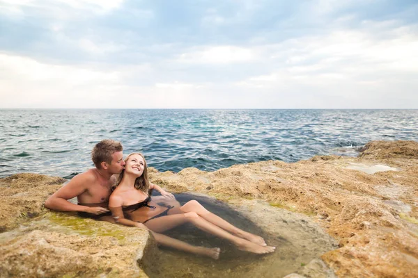 Jong gelukkig mooi paar vrouw en man genieten van tijd in natuurlijke rock zwembad met water met rotsen muur op de achtergrond — Stockfoto