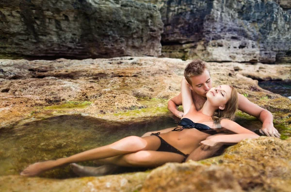 Jong gelukkig mooi paar vrouw en man genieten van tijd in natuurlijke rock zwembad met water met rotsen muur op de achtergrond — Stockfoto