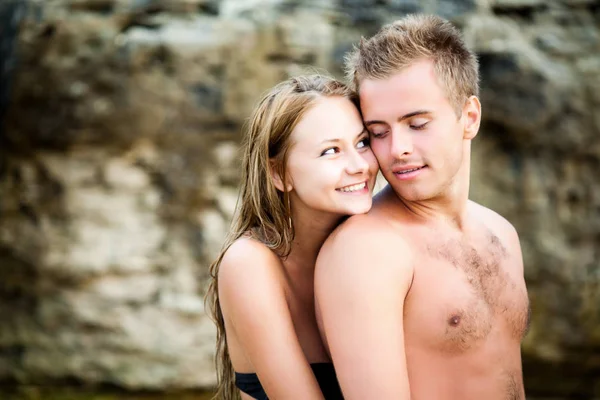 Jovem bela mulher sorridente abraçando de volta seu namorado feliz com rochas naturais no fundo — Fotografia de Stock
