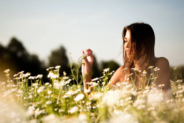 Jong sexy brunette vrouw liggend op gras en glimlachen op de zomer dag met groen natuur en rivier op de achtergrond — Stockfoto