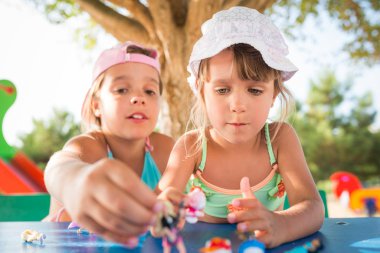Dışarıda oyuncak bebeklerle oynayan iki küçük tatlı kız.